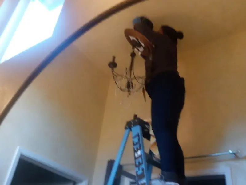 Electrician installing a chandelier in a Kearney residence